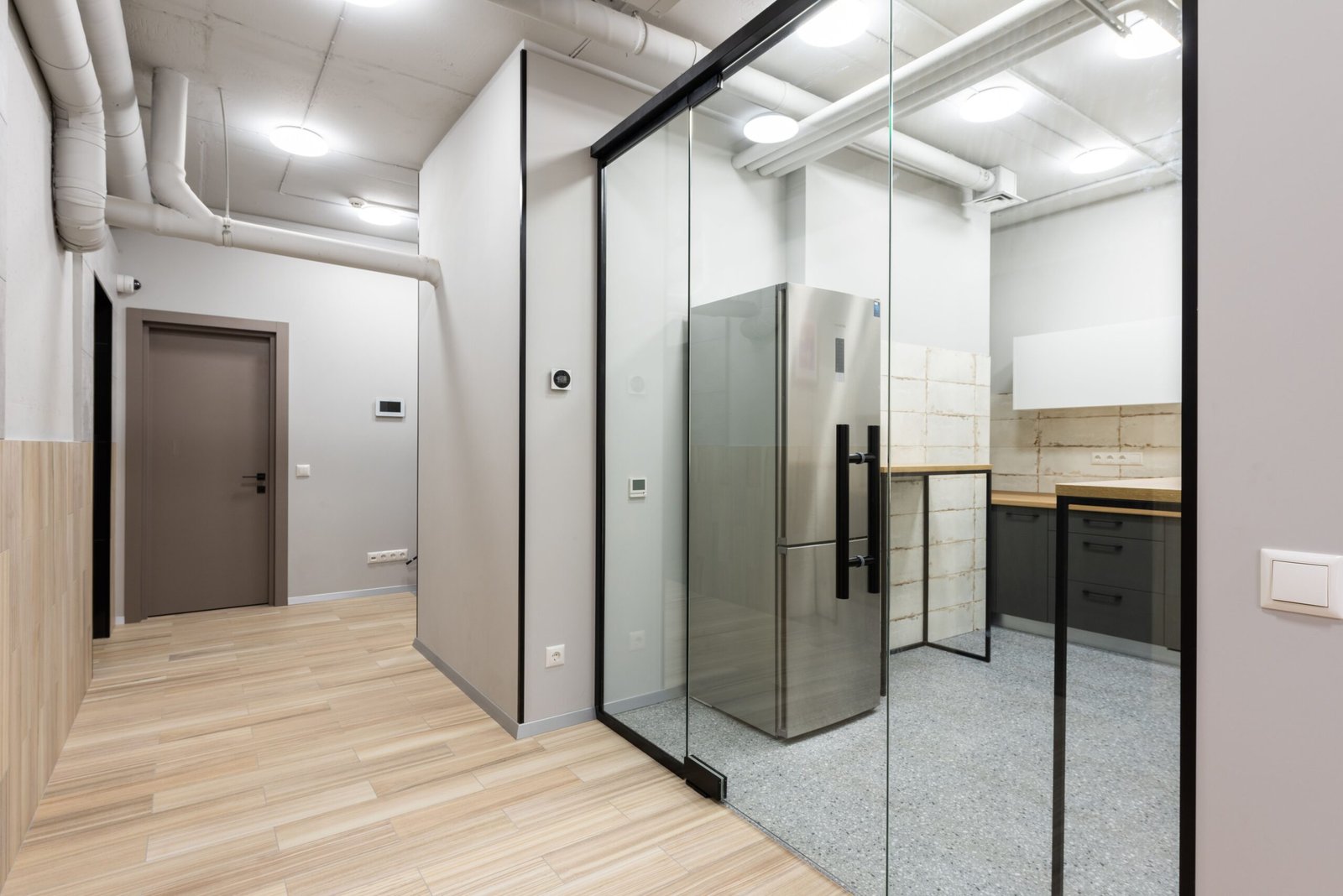 Interior of spacious hallway and kitchen with counters and appliances in contemporary workplace